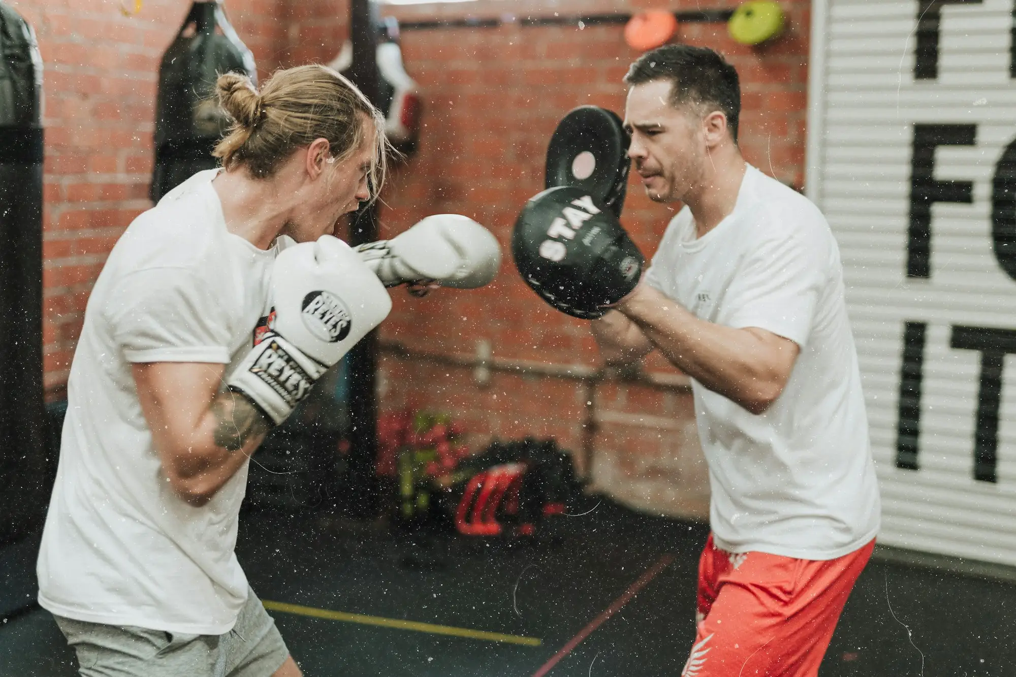 Trainer houdt pads vast terwijl een bokser slaat